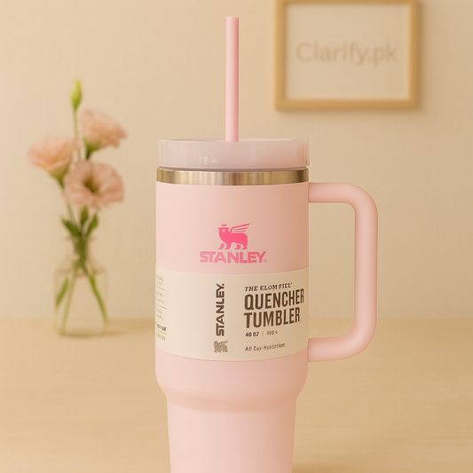 Pink Stanley quencher tumbler with handle and straw on wooden table with flower vase background