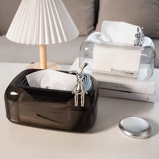 Black and clear sunken tissue box organizer with decorative silver bunny figures on a white table