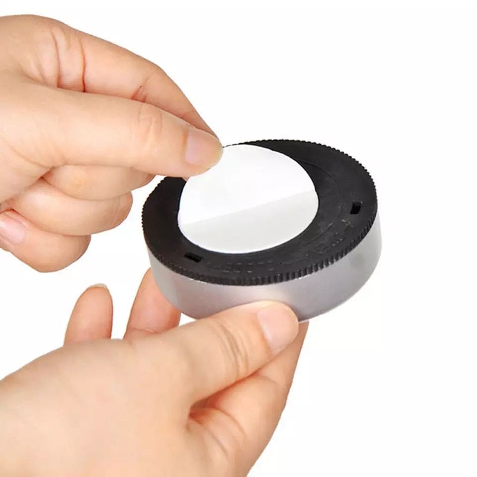 Person peeling adhesive backing from compact touch type car reading light for easy installation