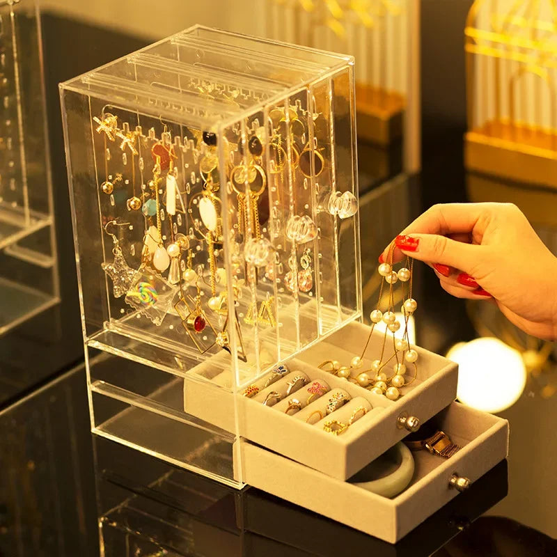 Clarify.pk transparent jewelry organizer box with multiple compartments holding earrings, rings, and necklaces
