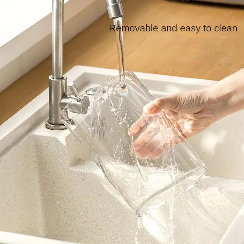 Clear transparent laundry detergent dispenser being cleaned under faucet in kitchen sink