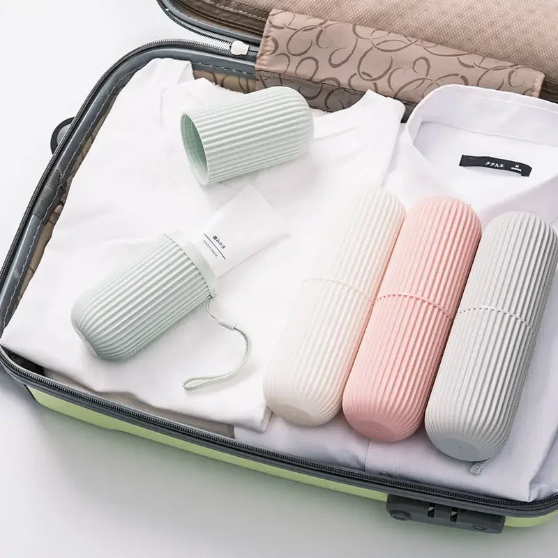 Travel toothpaste storage case set in pastel colors inside an open suitcase with folded clothes