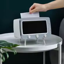 TV tissue box with phone holder in gray on white round table with hand pulling tissue