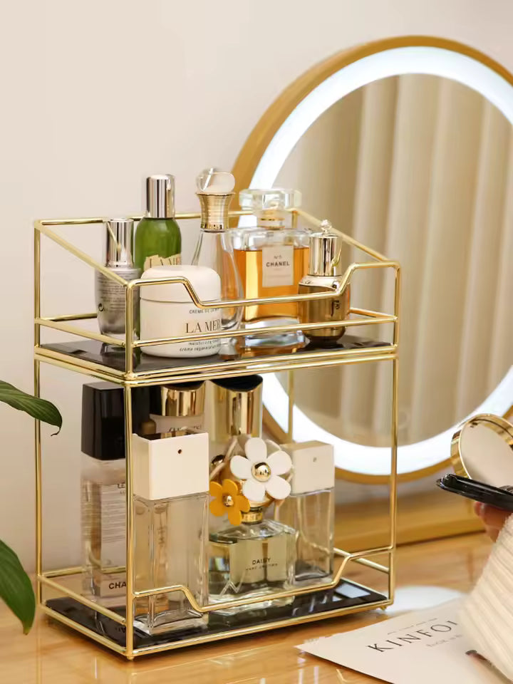 Gold metal desktop makeup organizer rack with multiple compartments holding perfume bottles and cosmetics