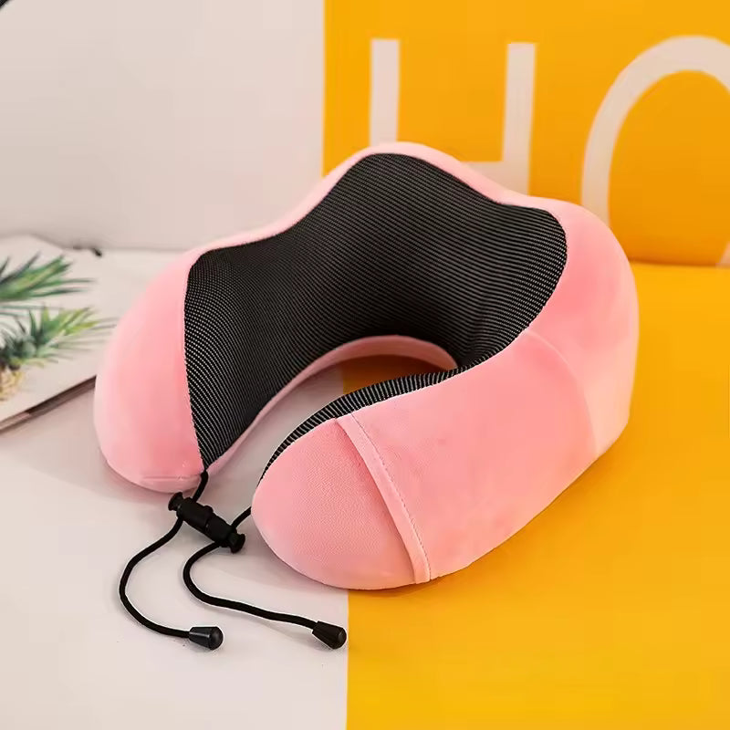 Pink U shaped memory foam neck pillow with black inner lining and adjustable strap for support