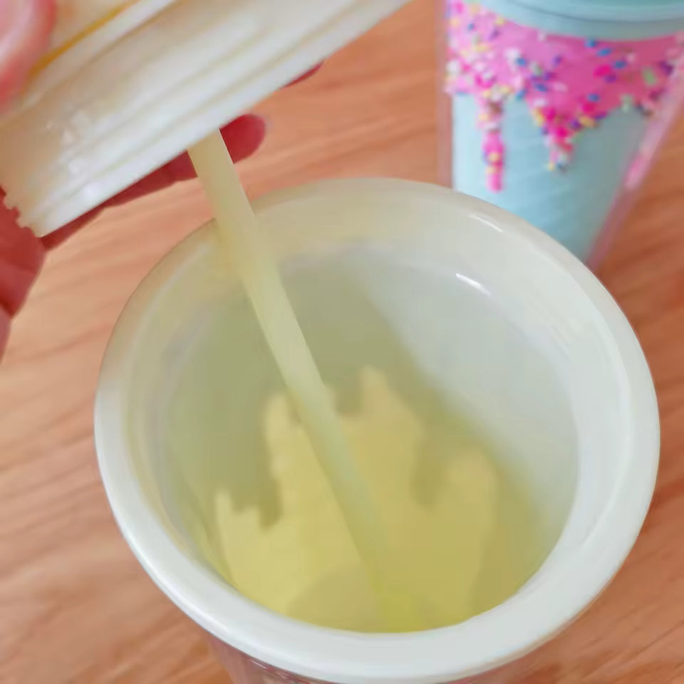 Inside view of unicorn water cup with straw showing liquid and lid being held