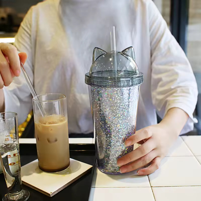 unicorn water cup with straw glitter design and cat ears held by person in white shirt