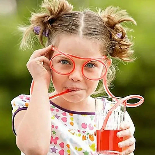 Child using unique drinking straws shaped like eyeglasses to drink red juice from a glass