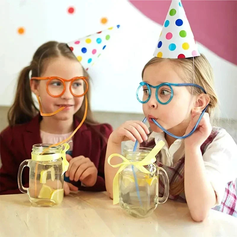 Two girls wearing party hats using unique drinking straws with lemon water in glass mugs