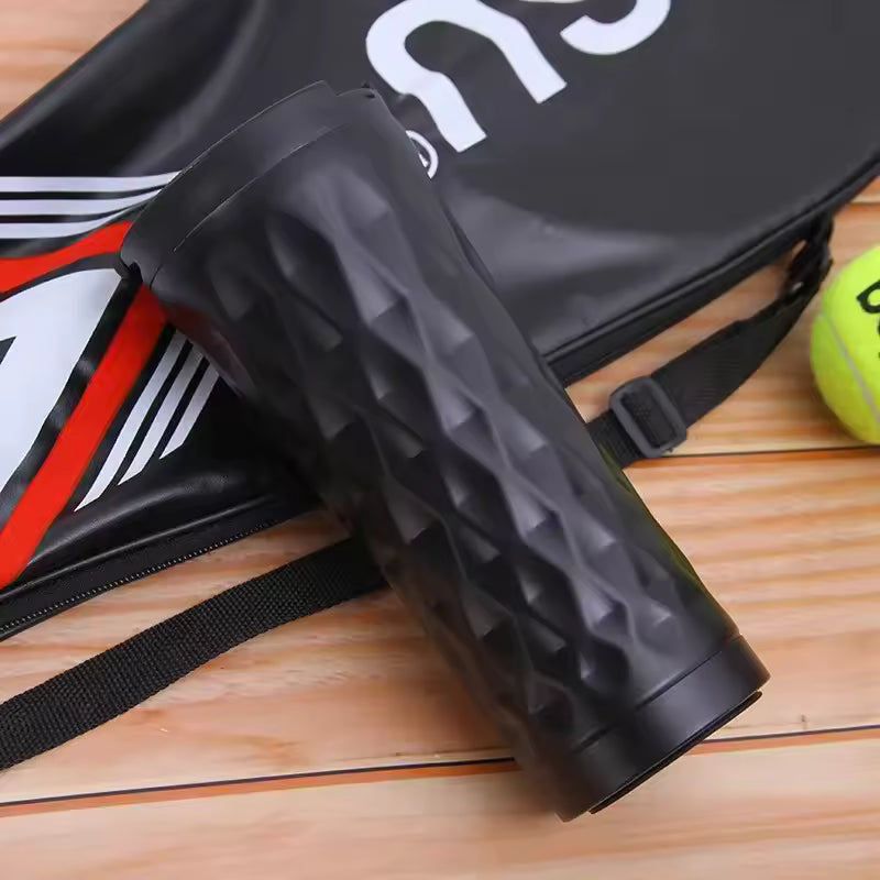 Black textured 500ml insulated travel mug placed on wooden surface near sports gear and tennis ball