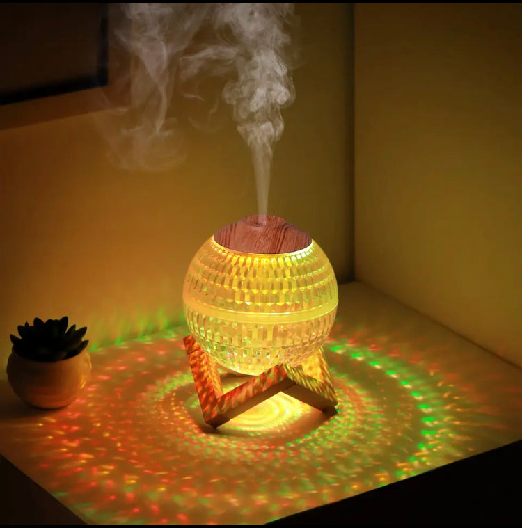 USB portable fragrance diffuser glowing with multicolor lights on wooden stand releasing mist on table