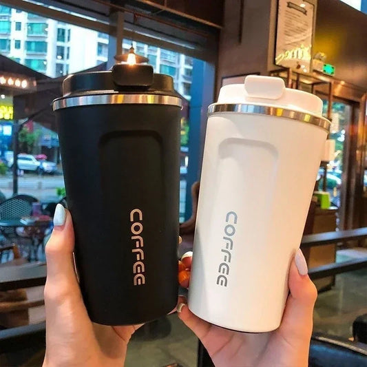 Black and white vacuum thermos bottle for tea and coffee held in hands in a cafe setting