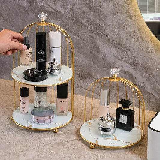 Elegant 2 tier cosmetic storage rack with gold frame and marble shelves holding various skincare and makeup products