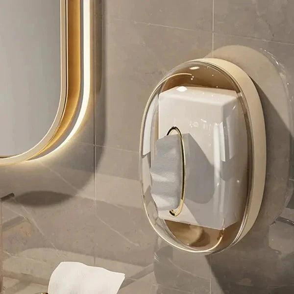 Clear acrylic tissue box wall-mounted on bathroom tile wall next to illuminated mirror