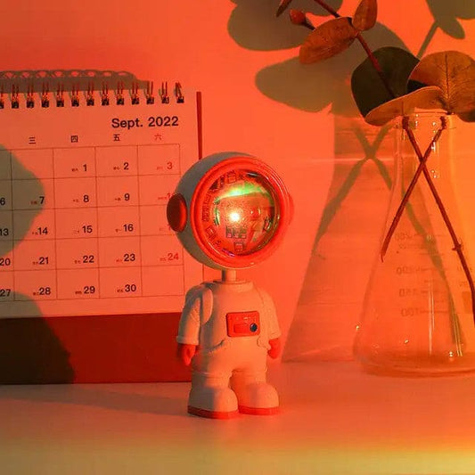 Clarify.pk astronaut starry sunset lamp casting warm orange light on a desk with calendar and vase