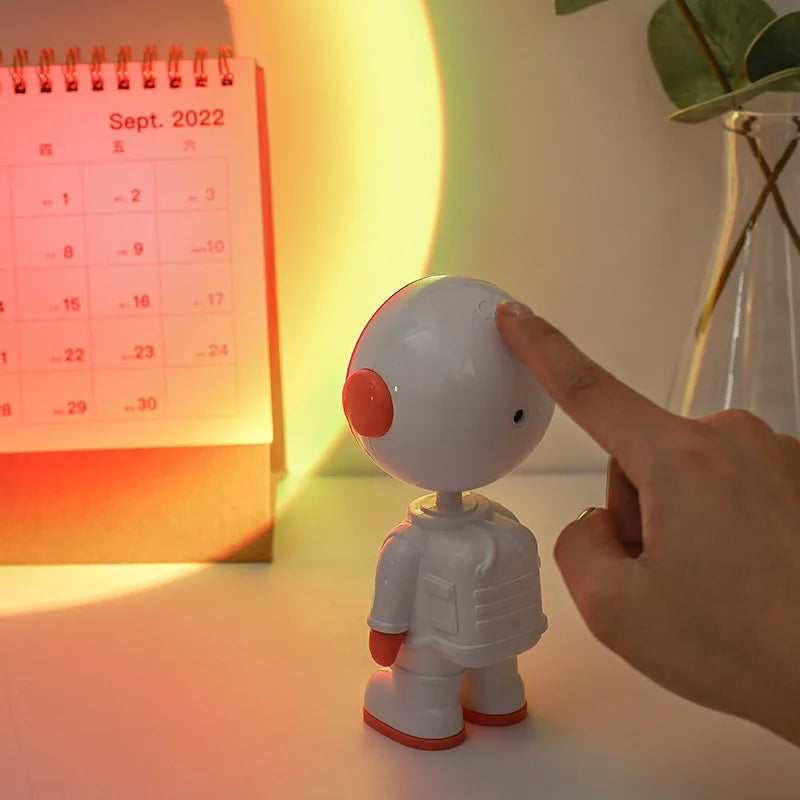 Hand turning on astronaut starry sunset lamp casting orange and yellow sunset light on a wall