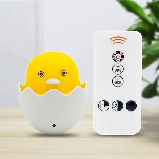 Egg shell night lamp for bedroom shaped like a yellow chick with remote control on wooden surface
