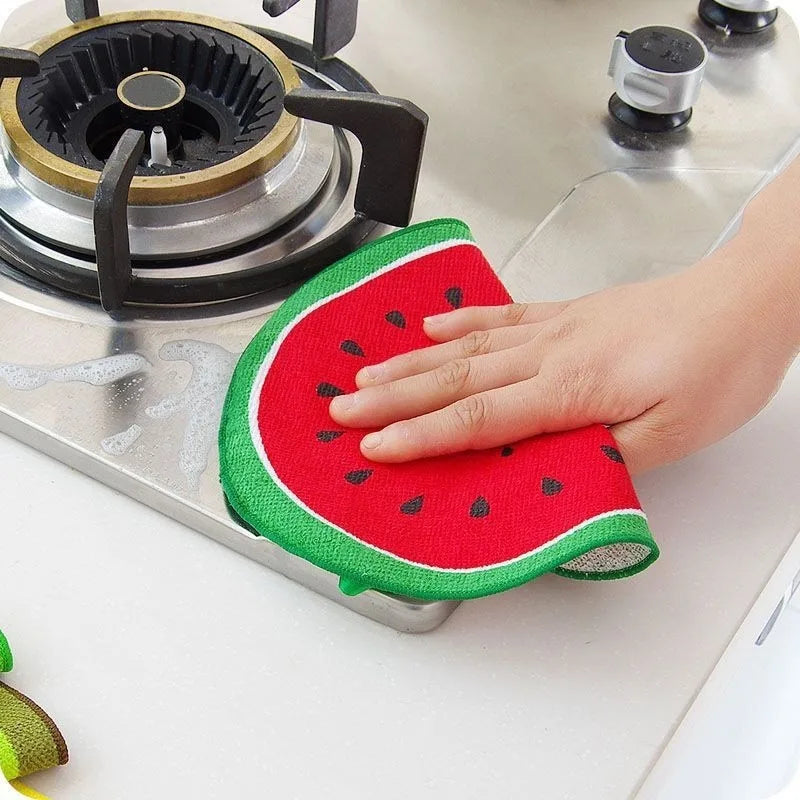 Hand using Clarify.pk fruit shape microfiber dishcloths to clean kitchen stove surface