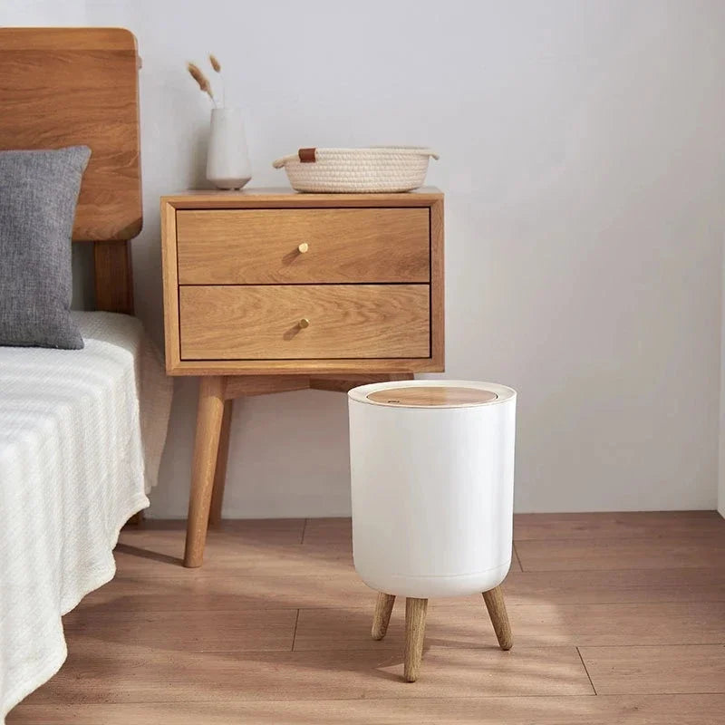 Modern wooden dustbin white with wooden legs next to wooden bedside table in bedroom