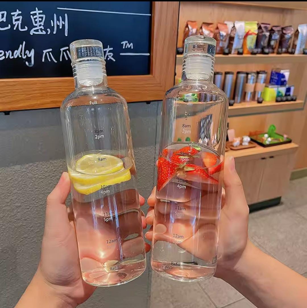 Two hands holding transparent plastic water bottle 500ml filled with fruit-infused water in a cafe setting