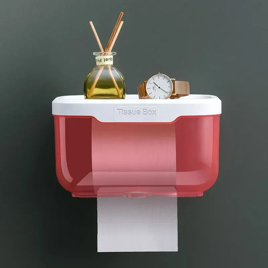 Wall mounted toilet paper holder with red tissue box and white top holding watch and diffuser