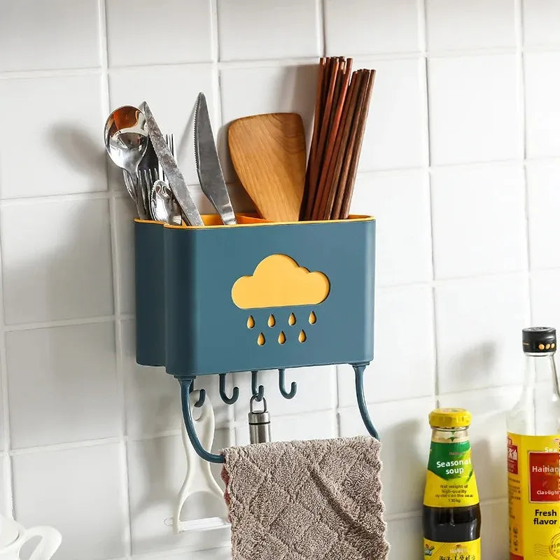 Blue and yellow wall mounted kitchen organizer holding utensils chopsticks and towel on white tiled wall