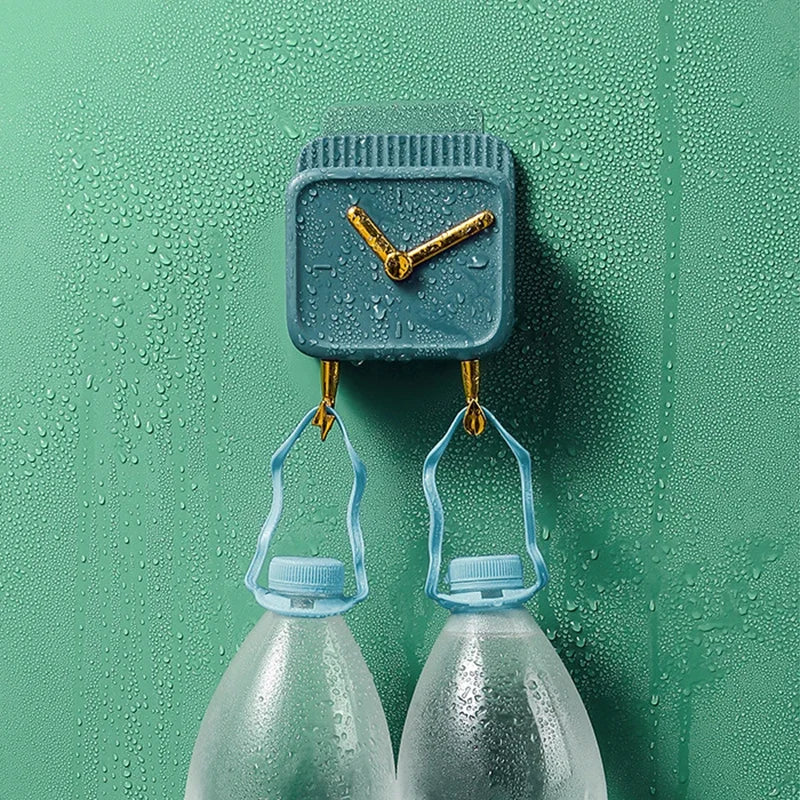 Blue wall mounted storage box with clock design and hooks holding two plastic bottles on wet green wall