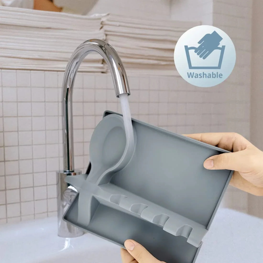 Gray kitchen spoon holder being washed under a modern kitchen faucet showing washable feature