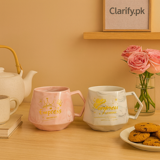 White and pink ceramic mugs with gold Empress design on wooden table near pink roses and cookies