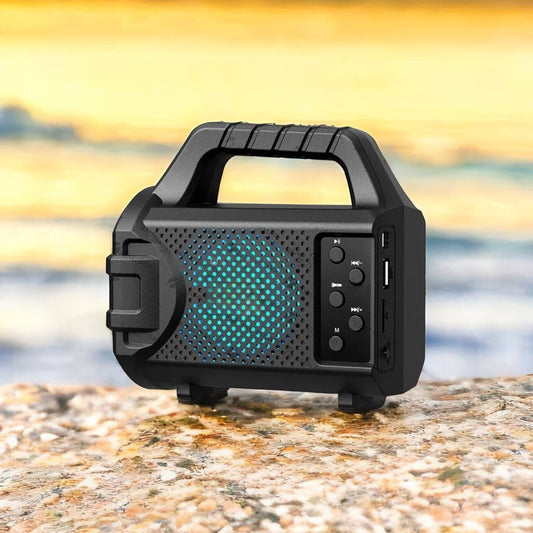 Wireless portable speaker with radio in black with handle and control buttons on rocky surface