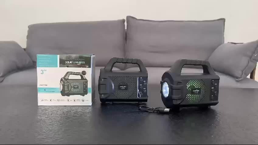 Wireless portable speaker with radio in black with handle and USB charging cable on table