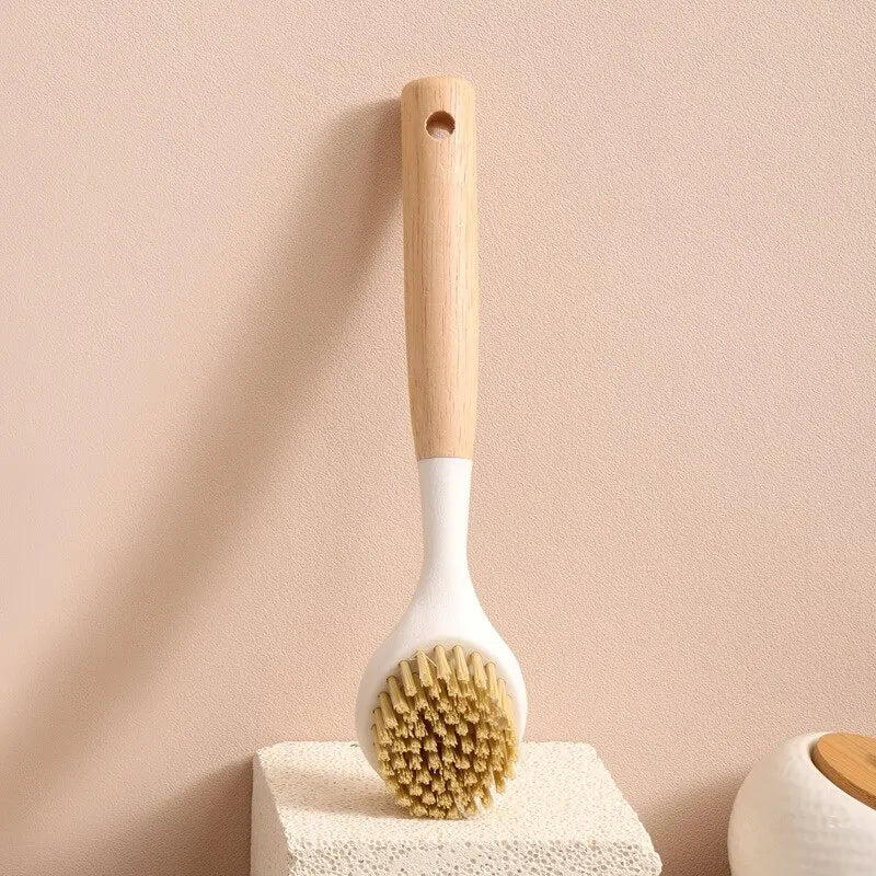 Wooden handle dishwashing brush with natural bristles standing on a textured white block