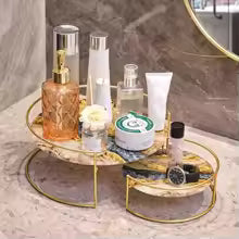 Clarify.pk wrought iron storage rack with two-tier gold frame holding cosmetics on marble countertop