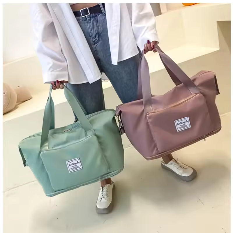 Two large capacity travel bags in green and pink colors held by a person wearing white shirt and jeans